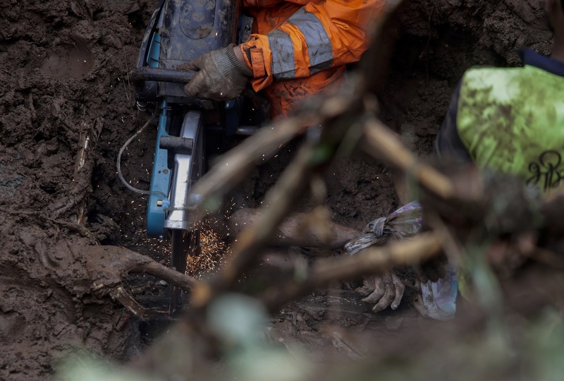 Rescuers carry a dead body of a man after a wall collapsed on several slum houses heavy monsoon rains in the Mahul area of Mumbai, India, Sunday, July 18, 2021. More than a dozen people were killed in the incident. (AP Photo/Rajanish Kakade)