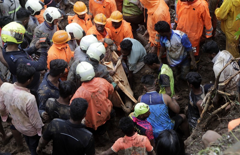 Rescuers carry a dead body of a man after a wall collapsed on several slum houses heavy monsoon rains in the Mahul area of Mumbai, India, Sunday, July 18, 2021. More than a dozen people were killed in the incident. (AP Photo/Rajanish Kakade)