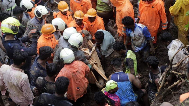 Rescuers carry a dead body of a man after a wall collapsed on several slum houses heavy monsoon rains in the Mahul area of Mumbai, India, Sunday, July 18, 2021. More than a dozen people were killed in the incident. (AP Photo/Rajanish Kakade)