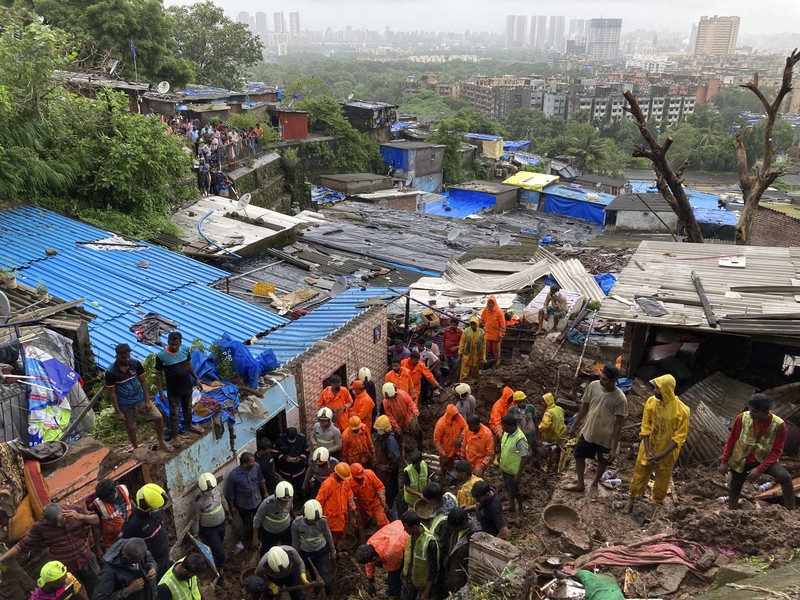 Rescuers carry a dead body of a man after a wall collapsed on several slum houses heavy monsoon rains in the Mahul area of Mumbai, India, Sunday, July 18, 2021. More than a dozen people were killed in the incident. (AP Photo/Rajanish Kakade)
