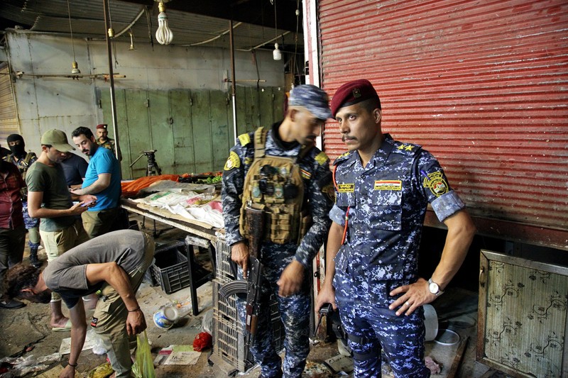 Ledakan bom di sebuah pasar sibuk di ibukota Irak, Baghdad People and security forces gather at the site of a bombing in Wahailat market in Sadr City, Iraq, Monday, July. 19, 2021. A roadside bomb attack targeted the Baghdad suburb Monday, killing several and wounding dozens of others at a crowded market, Iraqi security officials said. (AP Photo/Khalid Mohammed)