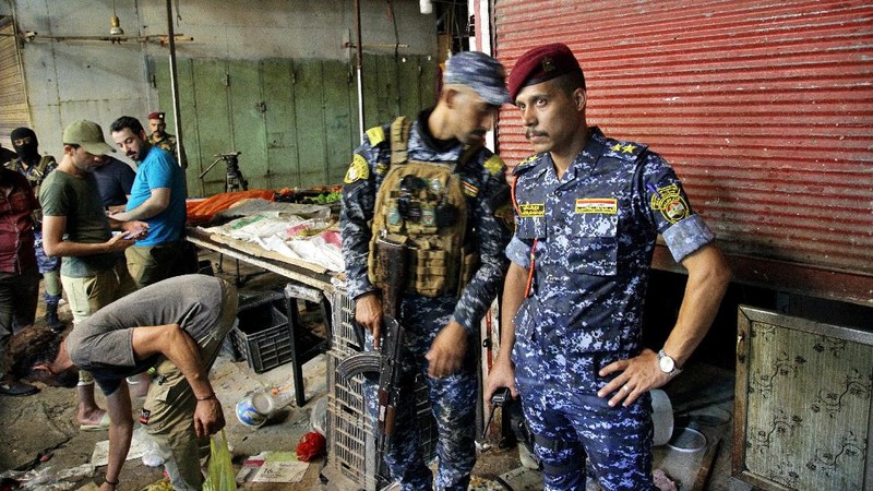 People and security forces gather at the site of a bombing in Wahailat market in Sadr City, Iraq, Monday, July. 19, 2021. A roadside bomb attack targeted the Baghdad suburb Monday, killing several and wounding dozens of others at a crowded market, Iraqi security officials said. (AP Photo/Khalid Mohammed)