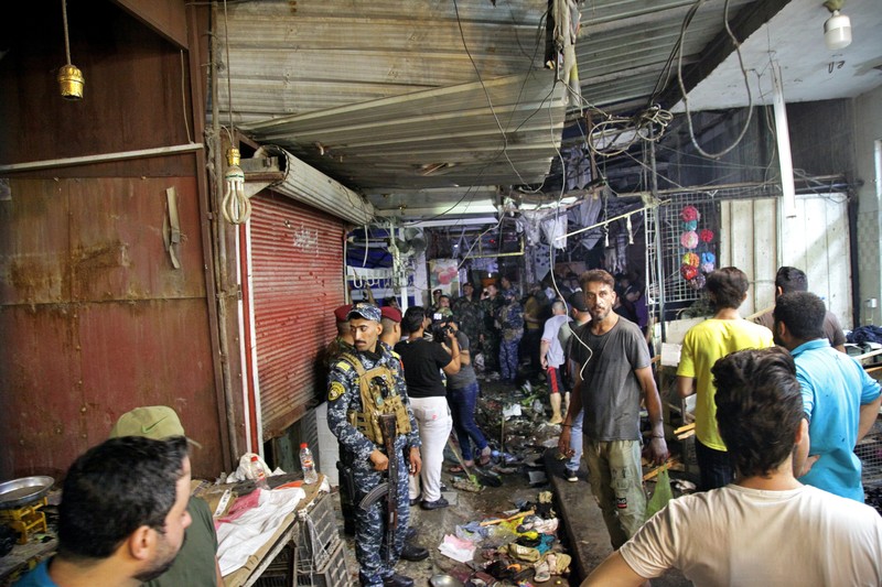 People and security forces gather at the site of a bombing in Wahailat market in Sadr City, Iraq, Monday, July. 19, 2021. A roadside bomb attack targeted the Baghdad suburb Monday, killing several and wounding dozens of others at a crowded market, Iraqi security officials said. (AP Photo/Khalid Mohammed)