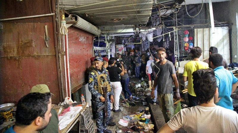 People and security forces gather at the site of a bombing in Wahailat market in Sadr City, Iraq, Monday, July. 19, 2021. A roadside bomb attack targeted the Baghdad suburb Monday, killing several and wounding dozens of others at a crowded market, Iraqi security officials said. (AP Photo/Khalid Mohammed)