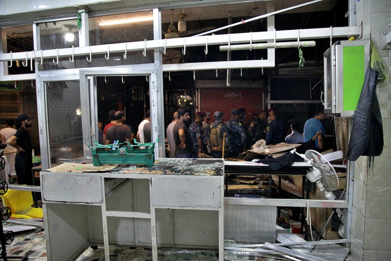 People and security forces gather at the site of a bombing in Wahailat market in Sadr City, Iraq, Monday, July. 19, 2021. A roadside bomb attack targeted the Baghdad suburb Monday, killing several and wounding dozens of others at a crowded market, Iraqi security officials said. (AP Photo/Khalid Mohammed)