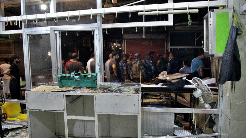 People and security forces gather at the site of a bombing in Wahailat market in Sadr City, Iraq, Monday, July. 19, 2021. A roadside bomb attack targeted the Baghdad suburb Monday, killing several and wounding dozens of others at a crowded market, Iraqi security officials said. (AP Photo/Khalid Mohammed)