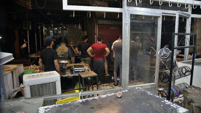 People and security forces gather at the site of a bombing in Wahailat market in Sadr City, Iraq, Monday, July. 19, 2021. A roadside bomb attack targeted the Baghdad suburb Monday, killing several and wounding dozens of others at a crowded market, Iraqi security officials said. (AP Photo/Khalid Mohammed)