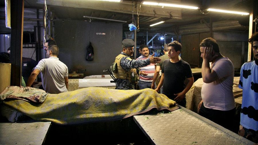 People and security forces gather at the site of a bombing in Wahailat market in Sadr City, Iraq, Monday, July. 19, 2021. A roadside bomb attack targeted the Baghdad suburb Monday, killing several and wounding dozens of others at a crowded market, Iraqi security officials said. (AP Photo/Khalid Mohammed)