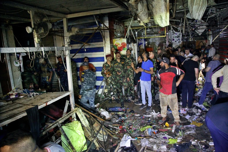 People and security forces gather at the site of a bombing in Wahailat market in Sadr City, Iraq, Monday, July. 19, 2021. A roadside bomb attack targeted the Baghdad suburb Monday, killing several and wounding dozens of others at a crowded market, Iraqi security officials said. (AP Photo/Khalid Mohammed)