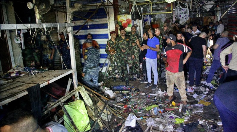 People and security forces gather at the site of a bombing in Wahailat market in Sadr City, Iraq, Monday, July. 19, 2021. A roadside bomb attack targeted the Baghdad suburb Monday, killing several and wounding dozens of others at a crowded market, Iraqi security officials said. (AP Photo/Khalid Mohammed)