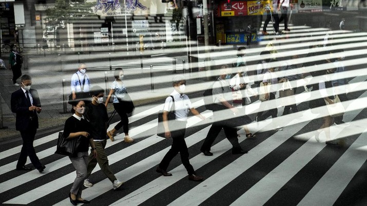 Aktivitas warga di Tokyo, Jepang Commuters are reflected in a bus window as they cross the street Thursday, July 15, 2021, in Tokyo. The pandemic-delayed 2020 Summer Olympics open on July 23 without spectators at most venues. (AP Photo/Jae C. Hong)
