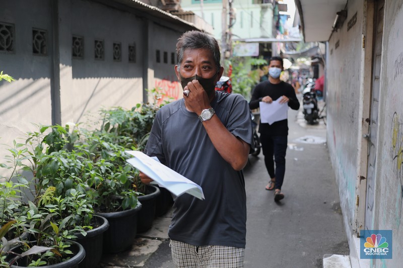 Petugas PT Pos Indonesia melakukan penyaluran Bantuan Sosial Tunai secara door to door di Kawasan Petojo Selatan, Jakarta, Rabu (21/7/2021). Tahun ini bansos (BST) ditargetkan untuk menjangkau hingga 10 juta keluarga penerima, penyaluran pun dilakukan secara bertahap. 
 (CNBC Indonesia/ Tri Susilo)