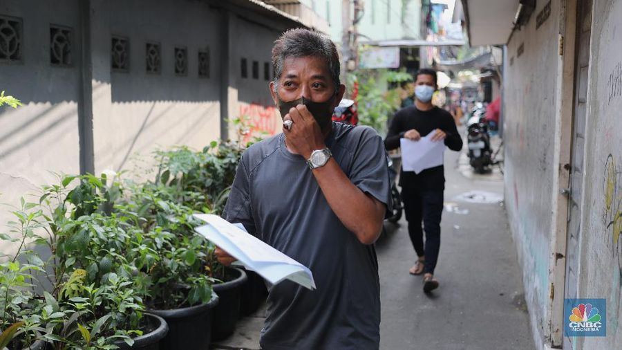 Petugas PT Pos Indonesia melakukan penyaluran Bantuan Sosial Tunai secara door to door di Kawasan Petojo Selatan, Jakarta, Rabu (21/7/2021). Tahun ini bansos (BST) ditargetkan untuk menjangkau hingga 10 juta keluarga penerima, penyaluran pun dilakukan secara bertahap. 
 (CNBC Indonesia/ Tri Susilo)