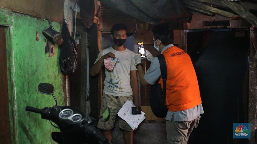 Petugas PT Pos Indonesia melakukan penyaluran Bantuan Sosial Tunai secara door to door di Kawasan Petojo Selatan, Jakarta, Rabu (21/7/2021). Tahun ini bansos (BST) ditargetkan untuk menjangkau hingga 10 juta keluarga penerima, penyaluran pun dilakukan secara bertahap. 
 (CNBC Indonesia/ Tri Susilo)