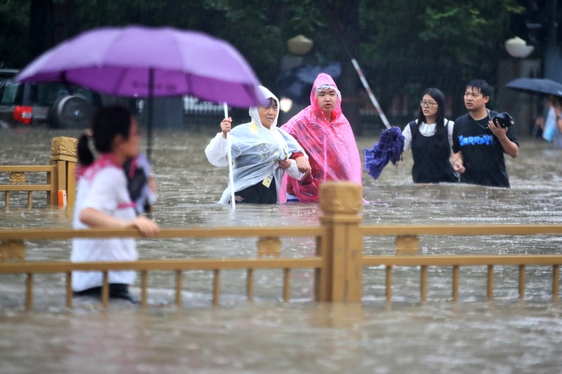 Banjir di China In this photo released by Xinhua News Agency, residents move their belongings across a flooded street in Zhengzhou in central China's Henan province on Wednesday, July 21, 2021. China's military has blasted a dam to release floodwaters threatening one of its most heavily populated provinces, as the death toll in widespread flooding rose to more than two dozens. (Zhu Xiang/Xinhua via AP)