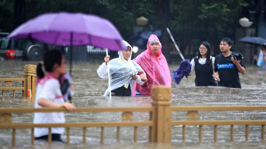 In this photo released by Xinhua News Agency, residents move their belongings across a flooded street in Zhengzhou in central China's Henan province on Wednesday, July 21, 2021. China's military has blasted a dam to release floodwaters threatening one of its most heavily populated provinces, as the death toll in widespread flooding rose to more than two dozens. (Zhu Xiang/Xinhua via AP)