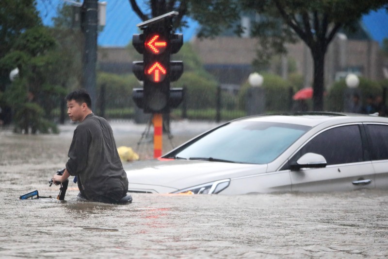 Banjir di China In this photo released by Xinhua News Agency, residents move their belongings across a flooded street in Zhengzhou in central China's Henan province on Wednesday, July 21, 2021. China's military has blasted a dam to release floodwaters threatening one of its most heavily populated provinces, as the death toll in widespread flooding rose to more than two dozens. (Zhu Xiang/Xinhua via AP)