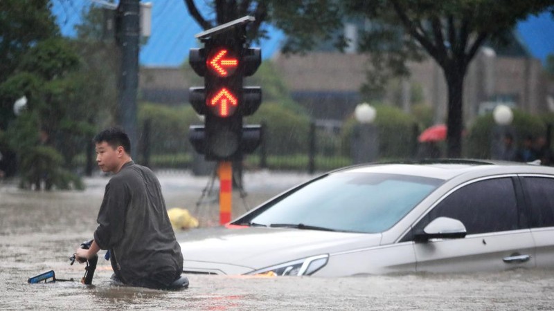 In this photo released by Xinhua News Agency, residents move their belongings across a flooded street in Zhengzhou in central China's Henan province on Wednesday, July 21, 2021. China's military has blasted a dam to release floodwaters threatening one of its most heavily populated provinces, as the death toll in widespread flooding rose to more than two dozens. (Zhu Xiang/Xinhua via AP)