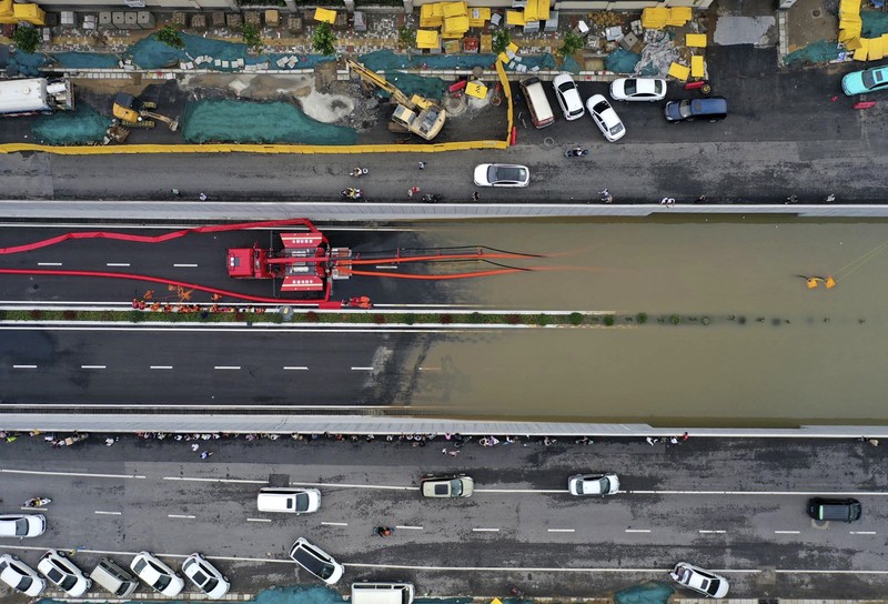 In this photo released by Xinhua News Agency, residents move their belongings across a flooded street in Zhengzhou in central China's Henan province on Wednesday, July 21, 2021. China's military has blasted a dam to release floodwaters threatening one of its most heavily populated provinces, as the death toll in widespread flooding rose to more than two dozens. (Zhu Xiang/Xinhua via AP)