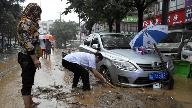 In this photo released by Xinhua News Agency, residents move their belongings across a flooded street in Zhengzhou in central China's Henan province on Wednesday, July 21, 2021. China's military has blasted a dam to release floodwaters threatening one of its most heavily populated provinces, as the death toll in widespread flooding rose to more than two dozens. (Zhu Xiang/Xinhua via AP)