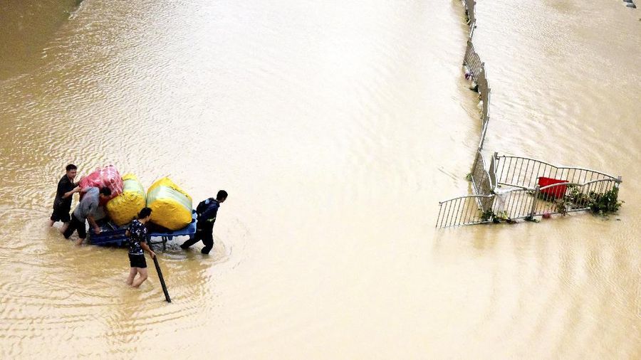 In this photo released by Xinhua News Agency, residents move their belongings across a flooded street in Zhengzhou in central China's Henan province on Wednesday, July 21, 2021. China's military has blasted a dam to release floodwaters threatening one of its most heavily populated provinces, as the death toll in widespread flooding rose to more than two dozens. (Zhu Xiang/Xinhua via AP)
