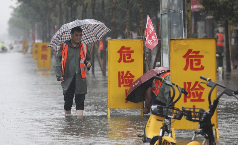 In this photo released by Xinhua News Agency, residents move their belongings across a flooded street in Zhengzhou in central China's Henan province on Wednesday, July 21, 2021. China's military has blasted a dam to release floodwaters threatening one of its most heavily populated provinces, as the death toll in widespread flooding rose to more than two dozens. (Zhu Xiang/Xinhua via AP)