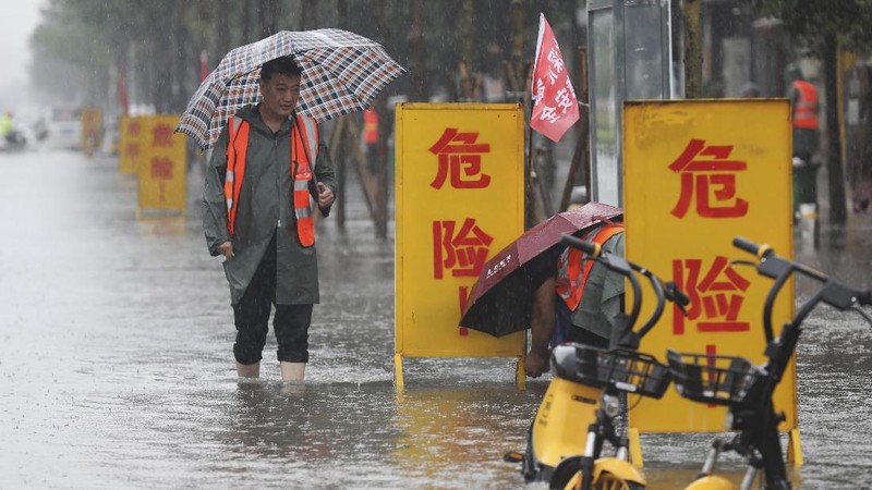 In this photo released by Xinhua News Agency, residents move their belongings across a flooded street in Zhengzhou in central China's Henan province on Wednesday, July 21, 2021. China's military has blasted a dam to release floodwaters threatening one of its most heavily populated provinces, as the death toll in widespread flooding rose to more than two dozens. (Zhu Xiang/Xinhua via AP)