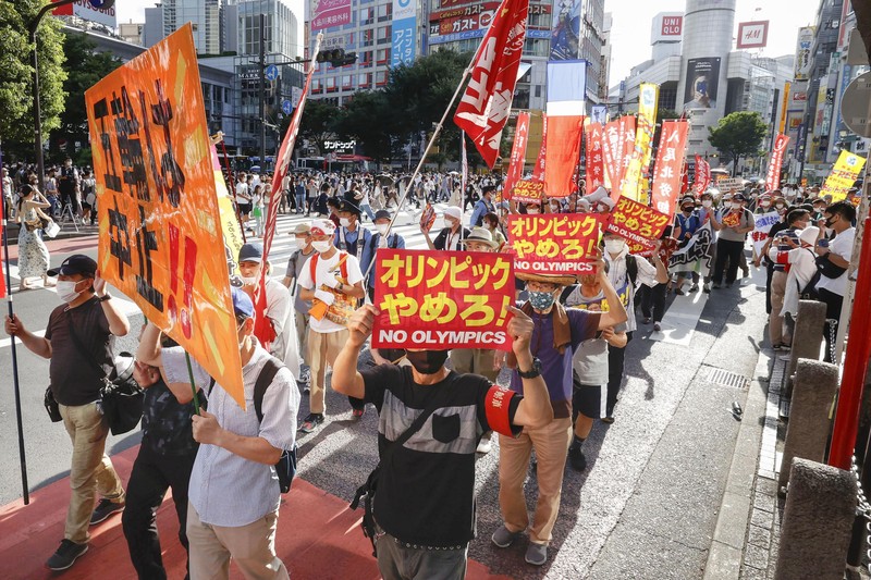 Anti-Olympics protesters march with banners in Tokyo on the opening day of the Tokyo 2020 Olympics Friday, July 23, 2021. A sign, center, reads 