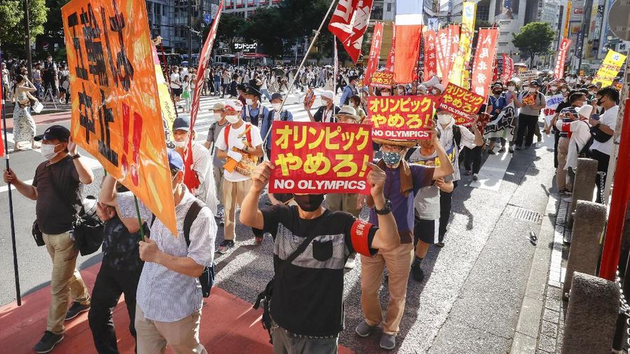 Anti-Olympics protesters march with banners in Tokyo on the opening day of the Tokyo 2020 Olympics Friday, July 23, 2021. A sign, center, reads 