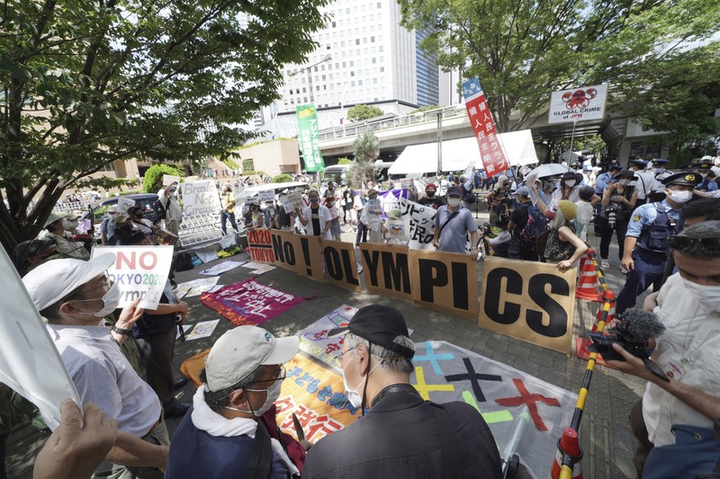 Anti-Olympics protesters march with banners in Tokyo on the opening day of the Tokyo 2020 Olympics Friday, July 23, 2021. A sign, center, reads 