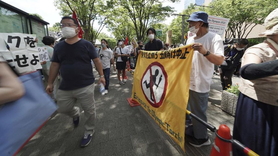 Anti-Olympics protesters march with banners in Tokyo on the opening day of the Tokyo 2020 Olympics Friday, July 23, 2021. A sign, center, reads 