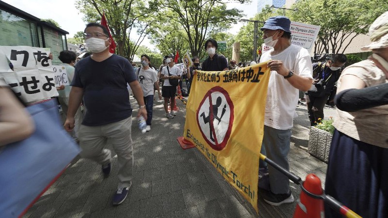 Anti-Olympics protesters march with banners in Tokyo on the opening day of the Tokyo 2020 Olympics Friday, July 23, 2021. A sign, center, reads 
