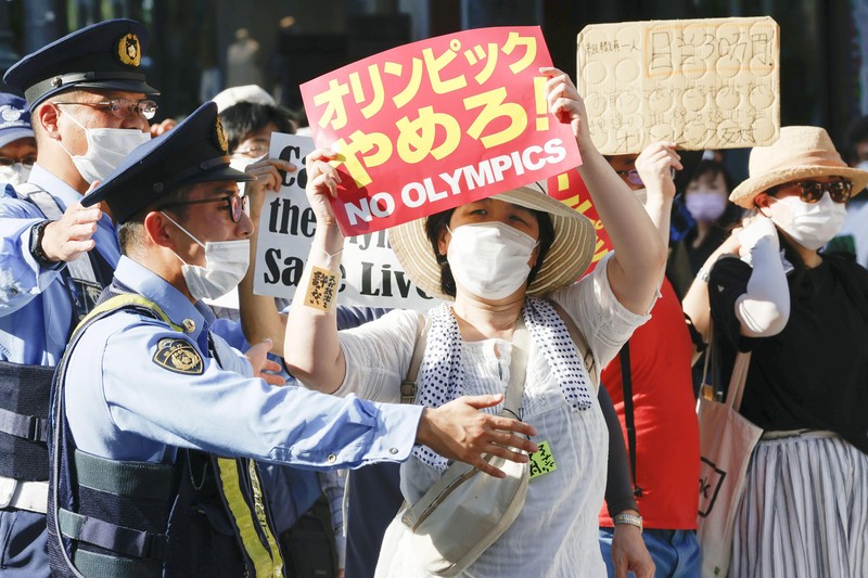Anti-Olympics protesters march with banners in Tokyo on the opening day of the Tokyo 2020 Olympics Friday, July 23, 2021. A sign, center, reads 
