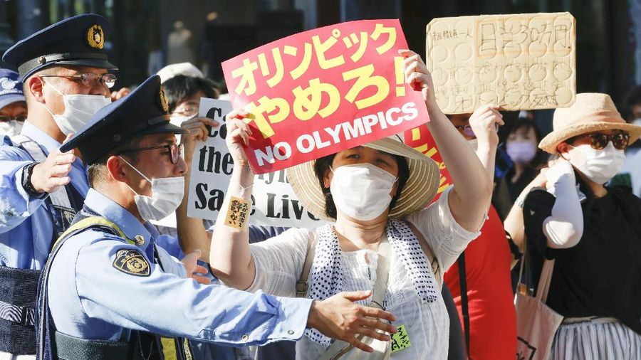 Anti-Olympics protesters march with banners in Tokyo on the opening day of the Tokyo 2020 Olympics Friday, July 23, 2021. A sign, center, reads 