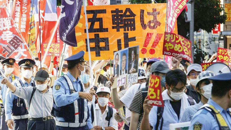 Anti-Olympics protesters march with banners in Tokyo on the opening day of the Tokyo 2020 Olympics Friday, July 23, 2021. A sign, center, reads 