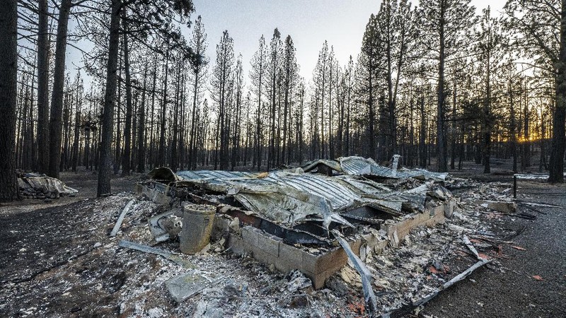 A sign damaged by the Bootleg Fire stands among the haze on Thursday, July 22, 2021, near Paisley, Ore. (AP Photo/Nathan Howard)