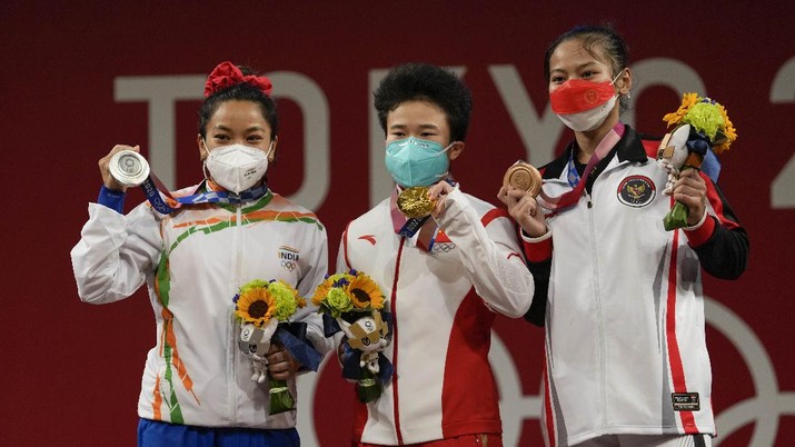 Peraih medali emas, Hou Zhihui dari China, tengah, berdiri bersama peraih medali perak Mirabai Chanu Saikhom dari India, kiri, dan peraih medali perunggu Windy Cantika Aisah dari Indonesia, kanan. (AP/Luca Bruno)