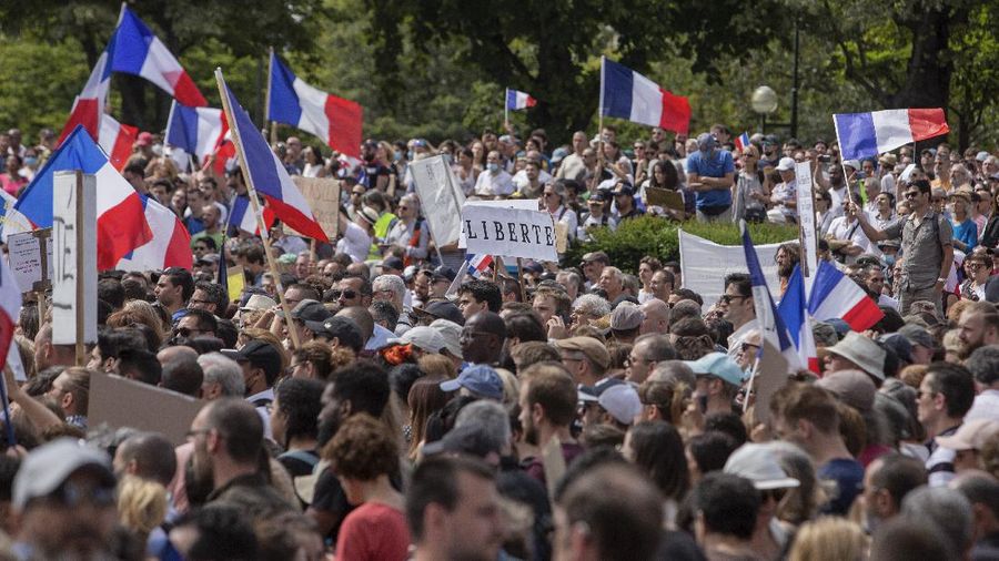 Thousands of protesters gather at Place Trocadero near the Eiffel Tower attend a demonstration in Paris, France, Saturday July 24, 2021, against the COVID-19 pass which grants vaccinated individuals greater ease of access to venues. (AP Photo/Rafael Yaghobzadeh)