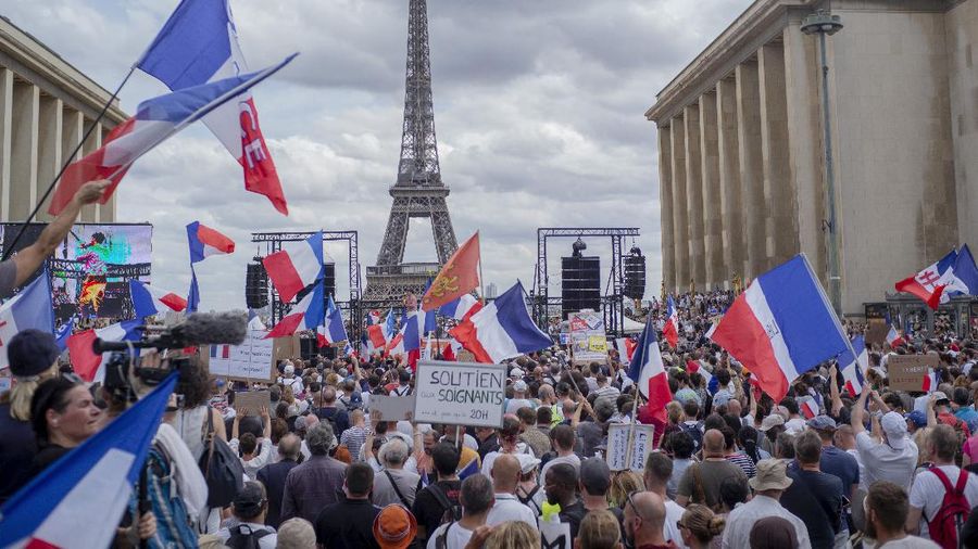 Thousands of protesters gather at Place Trocadero near the Eiffel Tower attend a demonstration in Paris, France, Saturday July 24, 2021, against the COVID-19 pass which grants vaccinated individuals greater ease of access to venues. (AP Photo/Rafael Yaghobzadeh)