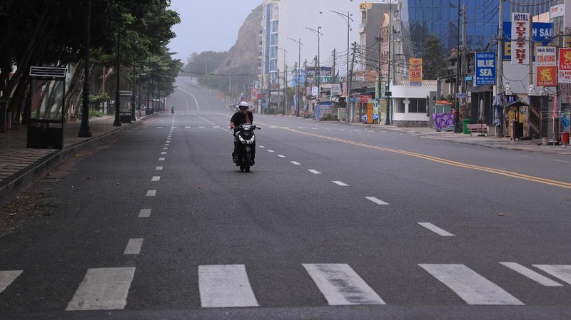 People ride on a motorcycle through a quiet intersection in Ho Chi Minh City, Vietnam, Monday, Aug. 23, 2021. Vietnam's largest metropolis Ho Chi Minh City has ordered a strict lockdown to help curb a worsening outbreak of the pandemic. (Bui Van Lanh/VNA via AP)
