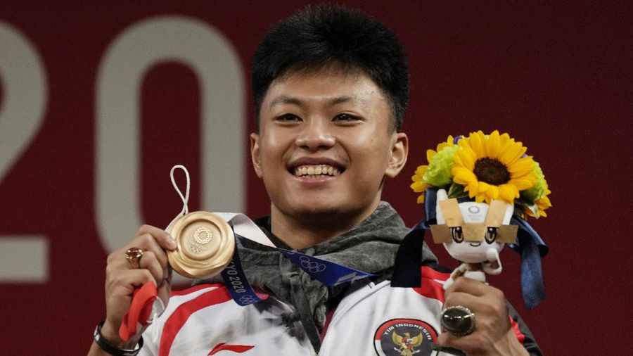 Rhamat Erwin Abdullah of Indonesia celebrates on the podium after winning the bronze medal in the men's 73kg weightlifting event, at the 2020 Summer Olympics, Wednesday, July 28, 2021, in Tokyo, Japan. (AP Photo/Luca Bruno)