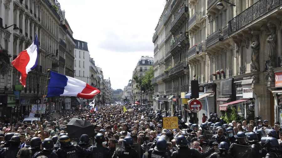 Protestors march waving French flags during a demonstration in Paris, France, Saturday, July 31, 2021. Demonstrators gathered in several cities in France on Saturday to protest against the COVID-19 pass, which grants vaccinated individuals greater ease of access to venues. (AP Photo/Adrienne Surprenant)