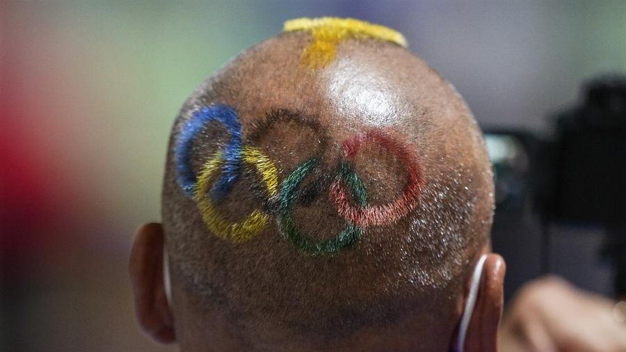 Mongolian coach Undralbat Lkhagva has the Olympic rings cut and dyed into his hair as he watches the women's 10-meter air pistol at the Asaka Shooting Range in the 2020 Summer Olympics, Sunday, July 25, 2021, in Tokyo, Japan. (AP Photo/Alex Brandon)