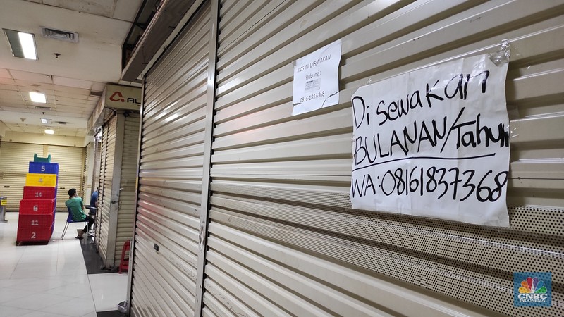 Pengunjung melintas di kios yang terpampang tulisan Pengunjung melintas di kios yang terpampang tulisan