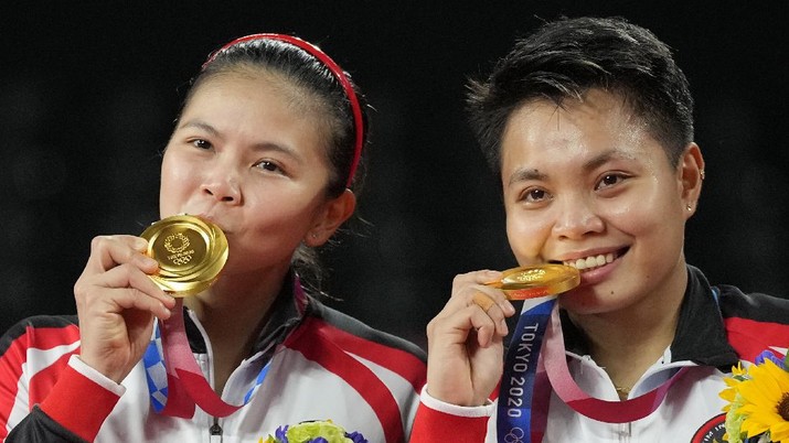 Indonesia's Greysia Polii, left, and Apriyani Rahayu celebrate with their gold medals after defeating China's Chen Qing Chen and Jia Yi Fan during their women's doubles gold medal match at the 2020 Summer Olympics, Monday, Aug. 2, 2021, in Tokyo, Japan. (AP Photo/Dita Alangkara)