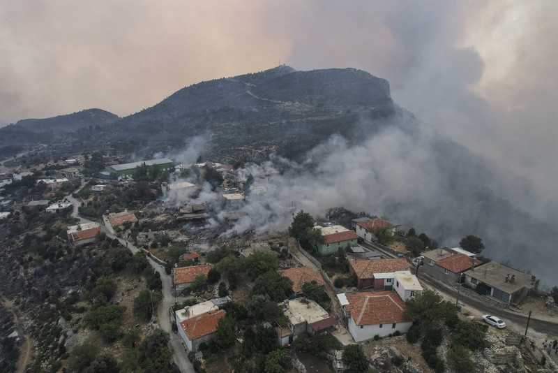 Turkey Wildfire People on the beach of smoke-engulfed Mazi area as wildfires rolled down the hill toward the seashore, in Bodrum, Mugla, Turkey, Sunday, Aug. 1, 2021. More than 100 wildfires have been brought under control in Turkey, according to officials. The forestry minister tweeted that five fires are continuing in the tourist destinations of Antalya and Mugla. (AP Photo/Emre Tazegul)