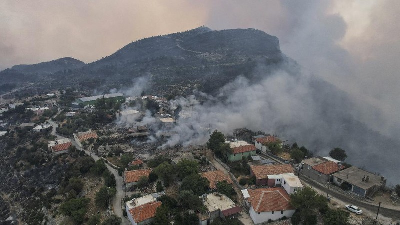 People on the beach of smoke-engulfed Mazi area as wildfires rolled down the hill toward the seashore, in Bodrum, Mugla, Turkey, Sunday, Aug. 1, 2021. More than 100 wildfires have been brought under control in Turkey, according to officials. The forestry minister tweeted that five fires are continuing in the tourist destinations of Antalya and Mugla. (AP Photo/Emre Tazegul)
