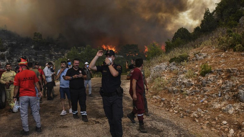 People on the beach of smoke-engulfed Mazi area as wildfires rolled down the hill toward the seashore, in Bodrum, Mugla, Turkey, Sunday, Aug. 1, 2021. More than 100 wildfires have been brought under control in Turkey, according to officials. The forestry minister tweeted that five fires are continuing in the tourist destinations of Antalya and Mugla. (AP Photo/Emre Tazegul)