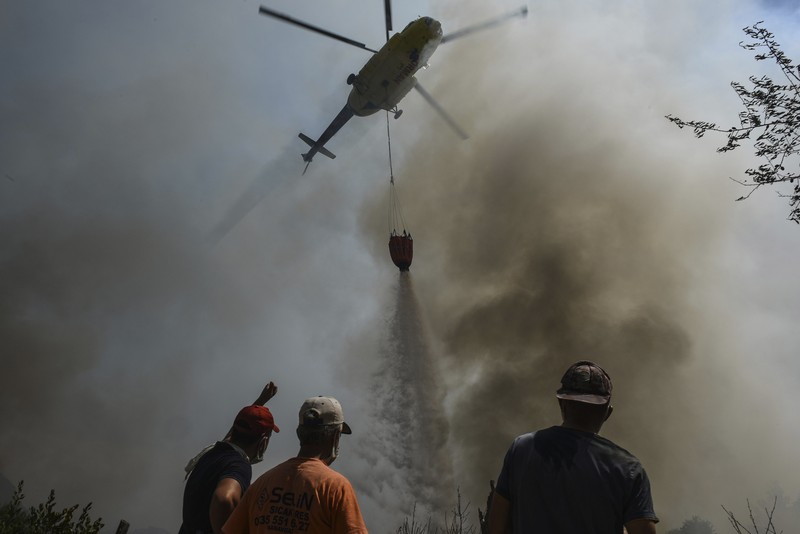 Turkey Wildfire People on the beach of smoke-engulfed Mazi area as wildfires rolled down the hill toward the seashore, in Bodrum, Mugla, Turkey, Sunday, Aug. 1, 2021. More than 100 wildfires have been brought under control in Turkey, according to officials. The forestry minister tweeted that five fires are continuing in the tourist destinations of Antalya and Mugla. (AP Photo/Emre Tazegul)