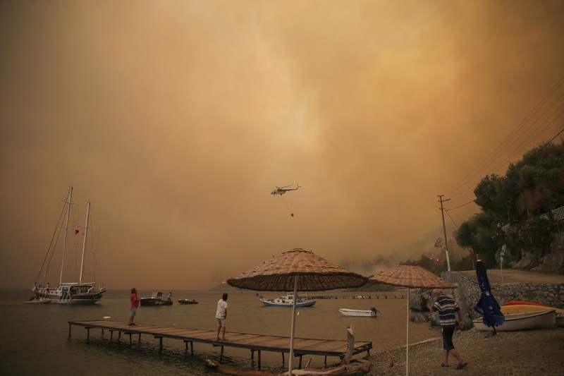 Turkey Wildfire People on the beach of smoke-engulfed Mazi area as wildfires rolled down the hill toward the seashore, in Bodrum, Mugla, Turkey, Sunday, Aug. 1, 2021. More than 100 wildfires have been brought under control in Turkey, according to officials. The forestry minister tweeted that five fires are continuing in the tourist destinations of Antalya and Mugla. (AP Photo/Emre Tazegul)